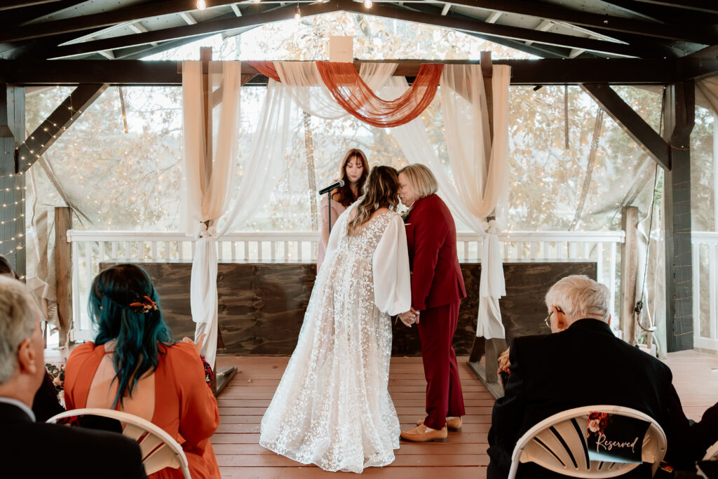 Two brides share a joyful moment during their wedding at the Old Schoolhouse in Merrimac, Wisconsin.