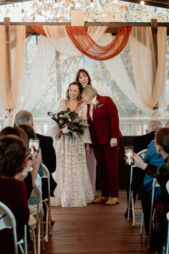 Two brides share a joyful moment during their wedding at the Old Schoolhouse in Merrimac, Wisconsin.