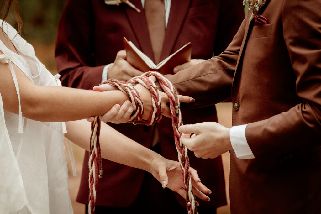 Bride and Groom preforming a handfasting during their ceremony at Burlap and Bells in Black River Falls, WI