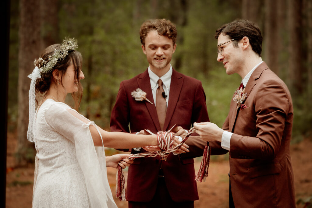 Bride and Groom preforming a handfasting during their ceremony at Burlap and Bells in Black River Falls, WI